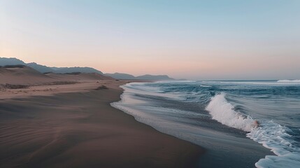 Fototapeta premium Peaceful morning on a deserted beach with soft waves and a clear sky transitioning from night to day