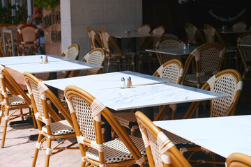 Outdoor tables and chairs on sidewalk in front of street cafe or restaurant. City life.