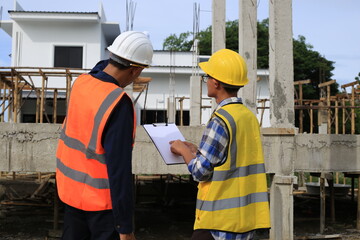 Young professional engineer in hat and blueprint paper is working...At the house construction site. Motivation: success, career growth. achieving goals