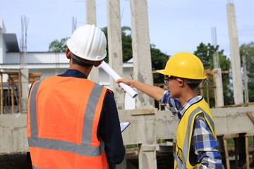 Young professional engineer in hat and blueprint paper is working...At the house construction site. Motivation: success, career growth. achieving goals