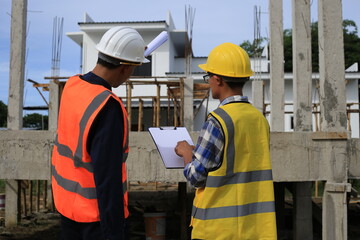 Young professional engineer in hat and blueprint paper is working...At the house construction site. Motivation: success, career growth. achieving goals