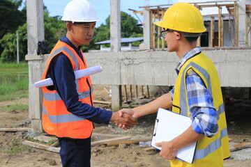 Young professional engineer in hat and blueprint paper is working...At the house construction site. Motivation: success, career growth. achieving goals