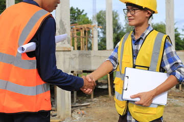 Young professional engineer in hat and blueprint paper is working...At the house construction site. Motivation: success, career growth. achieving goals