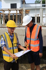 Young professional engineer in hat and blueprint paper is working...At the house construction site. Motivation: success, career growth. achieving goals