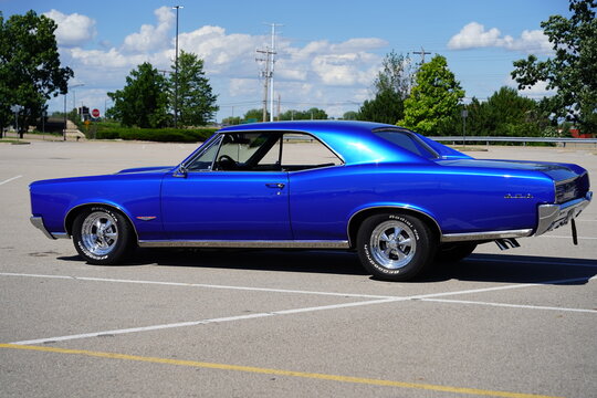 Royal Blue 1966 Pontiac GTO 2-door hardtop 389 Tri-Power V8 vintage car sits in parking lot.