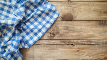 Top view of light wooden table with blue checkered tablecloth and space for text