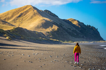 pretty girl enjoys a colorful sunset at black sand beach in north canterbury near kaikoura; new zealand south island