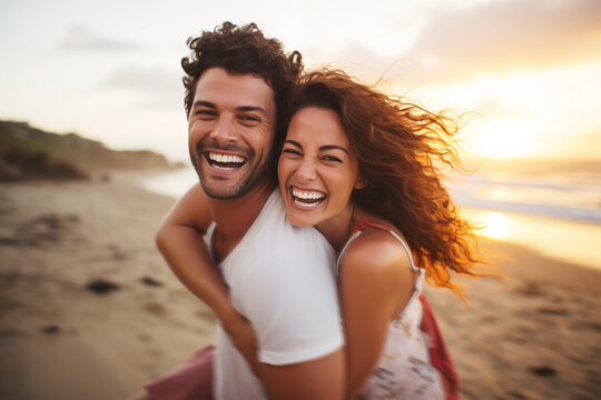 Young couple in their thirties on the beach laughing while riding piggyback at sunset
