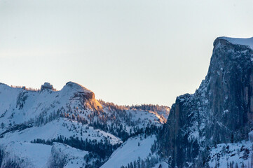 Early sunlight catching the snowcapped mountain tops of the Sierra nevada peaks in Yosemite national park, around sunrise on an early winter morning.