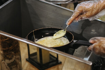 The process of baking a pancake in a metal frying pan. Pouring the dough on a hot surface
