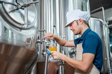 Asian brewer, Craft beer quality is overseen by an experienced brewer wearing an apron in the craft brewery.