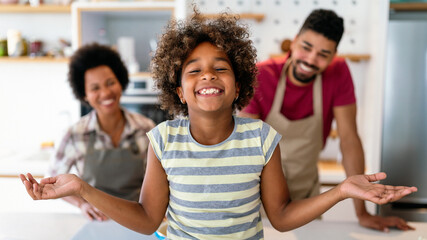 Happy black family in the kitchen having fun and cooking together. Healthy food at home.