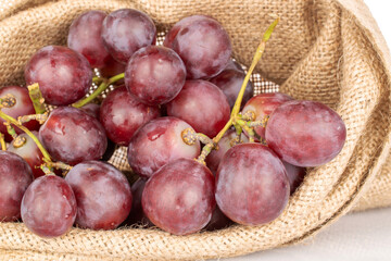 Bunch of sweet grapes in jute sack, macro, isolated on white background.