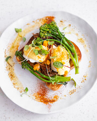 Gourmet Asian fusion toast slow cooked five spiced pulled pork on thick butter milk soft toast with two poached eggs, hollandaise sauce, crumbed salted duck eggs, broccolini, paprika and herbs