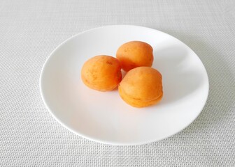 白い皿の上の生食用あんず３個（ハーコット）