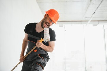 Funny and cheerful worker sings in a roller for painting the walls