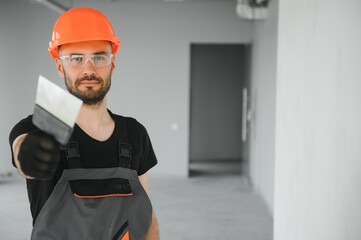 Professional worker plastering wall with putty knife indoors