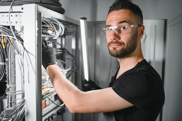 Repairman is busy and working with internet equipment and wires in server room