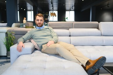 Young man buying sofa in furniture store