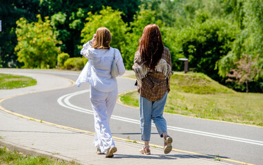 Obraz premium Two girlfriends walk along a path in the Park 