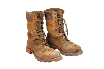 Pair of worn leather work boots with mud, isolated on a white background, showcasing durability and ruggedness.