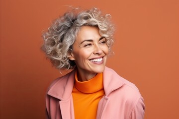 Portrait of a happy senior woman with curly hair on orange background