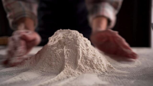 Baker working in a restaurant kitchen making a pile of flour on the table. Bakery and baking concept