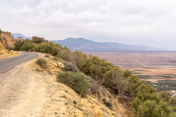 Arid Moroccan landscape near Marrakech, sparse vegetation, rolling hills, dry terrain, distant mountains