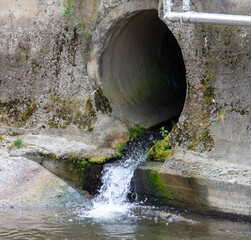 Water flows from a pipe into the river