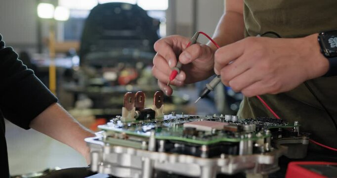 Auto mechanic inspecting and repairing electric car engine in a modern workshop. EV maintenance and service in progress. EV repair concept. Auto Service, Electric vehicle engine maintenance