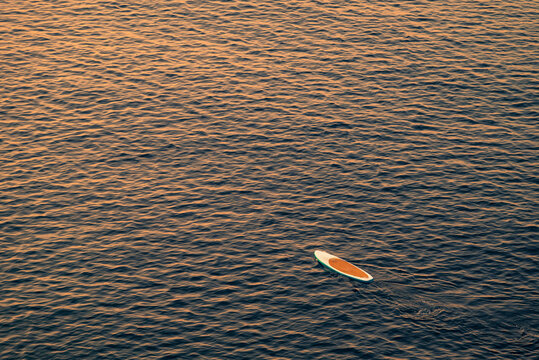 Stand up paddle board drifting over calm sea at sunrise