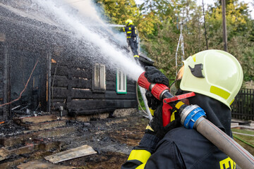 Fireman puts out the fire of an old wooden house in the mountains