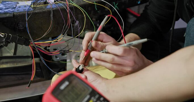 Hands of car mechanic working in auto repair service. They use specialized tools and equipment to ensure accuracy. Car repair service. Service man hands working with cables of auto