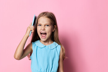 Young girl with angry expression holding a comb over her head while looking directly at the camera