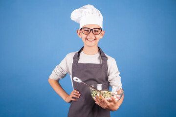 cheerful brunette boy cook in a chef's hat and apron prepares a salad. studio photo. My future...