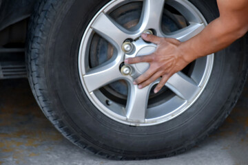 Mechanic male staff worker replacing and refiling air into flat car tire, working in local own garage auto service, soft focus.