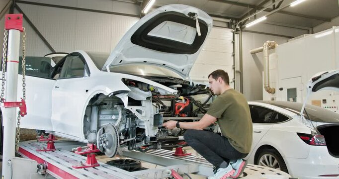 A mechanic working on a car repair in a modern, well-equipped auto workshop. The image shows the complex process of fixing a vehicle's body and components.