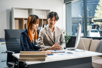  A businessman and businesswoman work late in the office, discussing strategies at a desk. They use technology and teamwork to plan and achieve success, demonstrating effective communication.