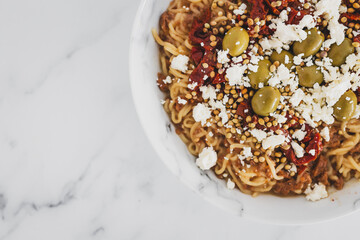 spaghetti noodles with sundried tomatoes green olives and crumbled fetta cheese