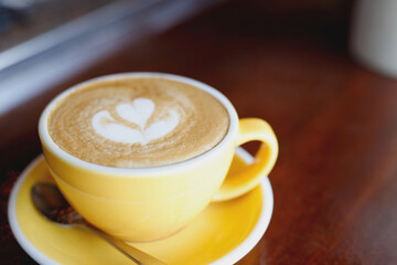 hot coffee cup latte art with spoon Serve ready to drink in cafe on wooden table coffee shop.  Leave copy space empty to write the side text. soft focus.