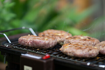 Burger meat on a barbecue grill close up, grilling burgers on an electric barbecue, smoke coming out of the meat