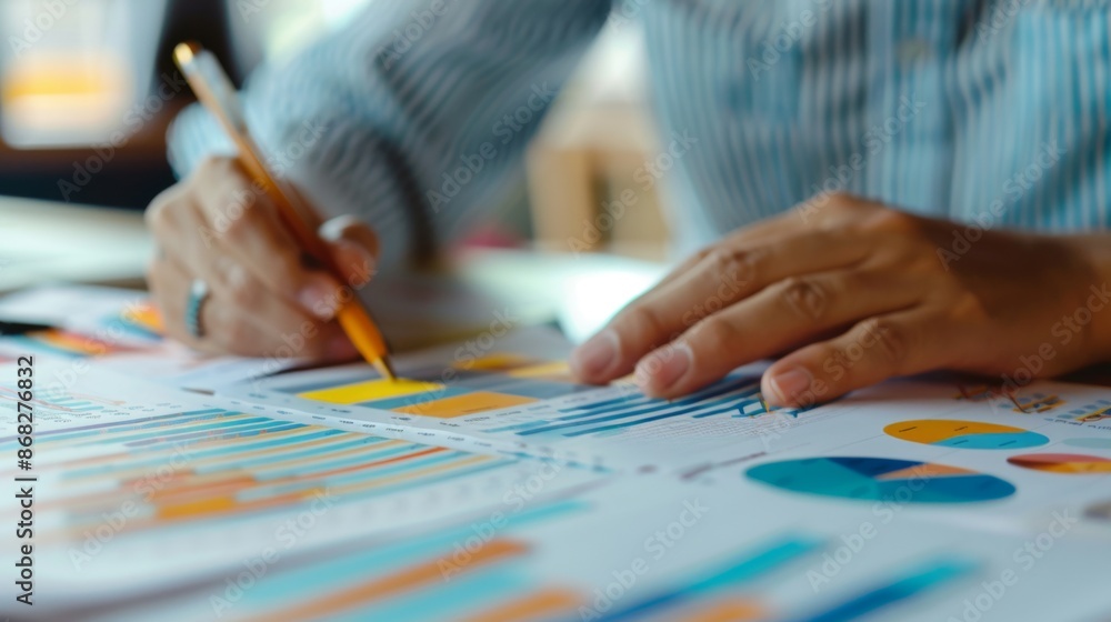 Poster a close-up of hands working on a financial report with printed graphs and charts, highlighting detai