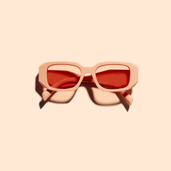 Stylish sunglasses with red Frame on peach color background, sunlight shadow, summer fashion...