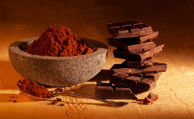 dark chocolate and bowl with cocoa powder, on wood..