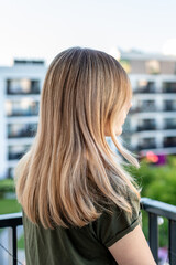 Young blonde girl with airtouch balayage on the balcony