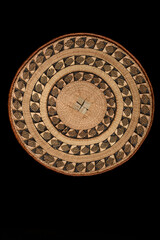 Traditional South African woven basket with geometric paterns on a black background.