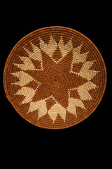 Traditional South African woven basket with geometric paterns on a black background.