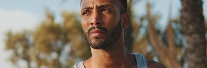 Fototapeta premium Close up, young bearded male fit athlete walks after training, looking away, panorama
