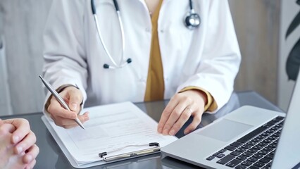 Doctor completing paperwork with patient. Close-up of a doctor's hands with forms, imparting...