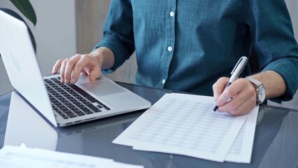 Businessman or professional auditor is analyzing data on laptop. Person in a blue shirt works with data sheet. Business concept